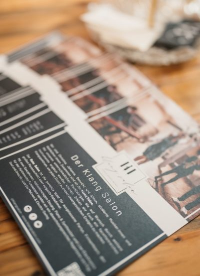 Flyer von Klang Salon liegen auf einem Messe-Stand aus